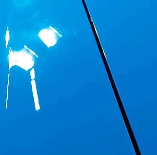 Close-up of glass-like reflections on freshly polished blue paint